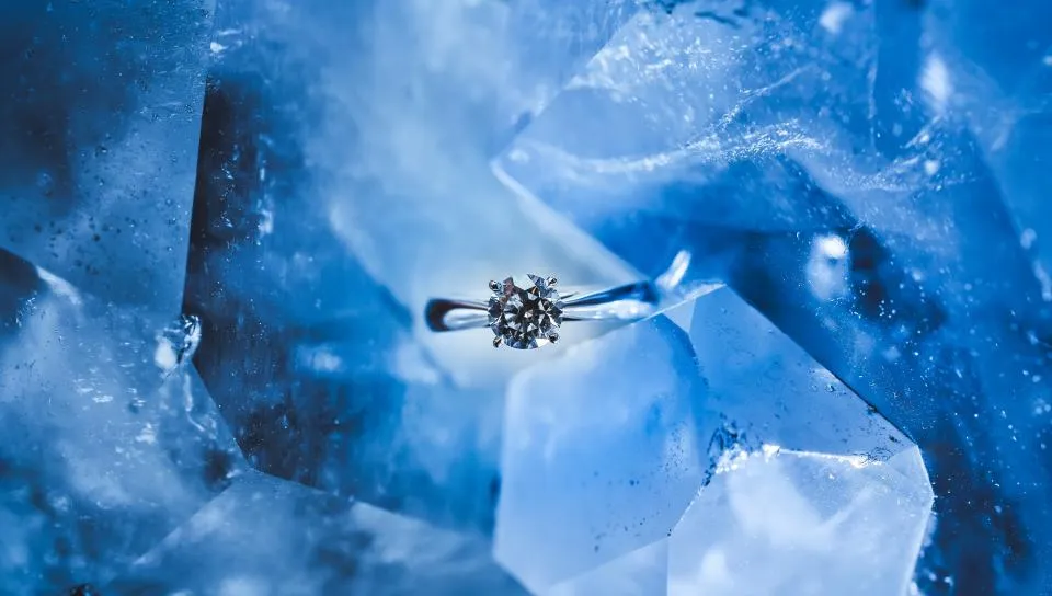Solitaire ring resting among blue crystal shards