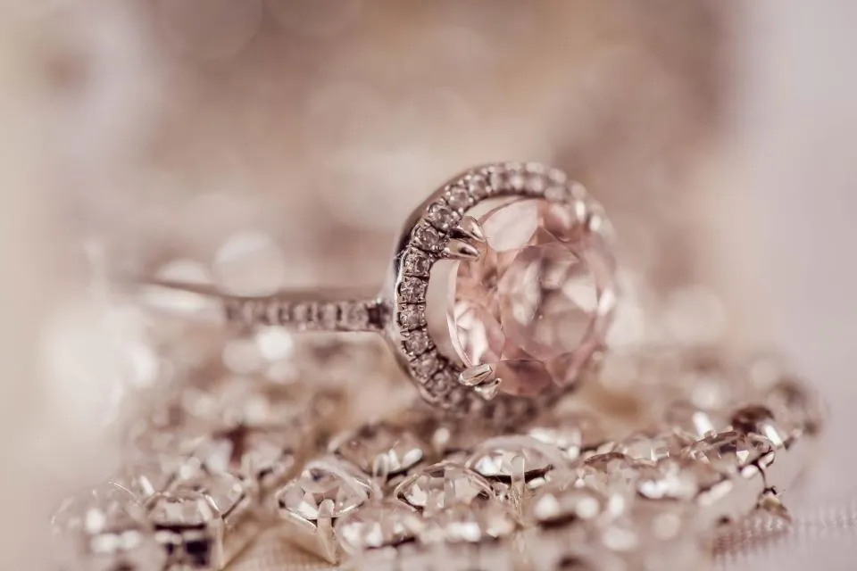 Pink gemstone set in a ring with a halo of small diamonds